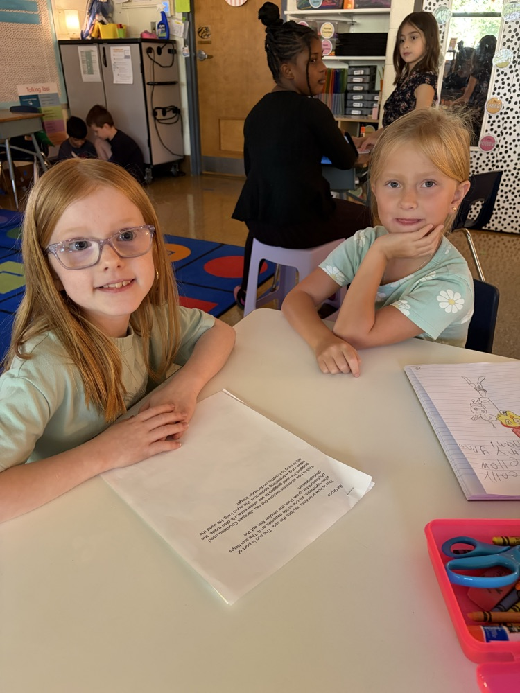 two students at desks reading essays