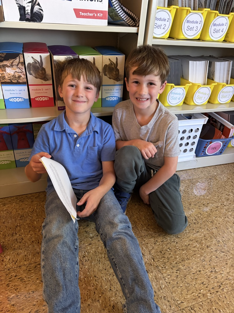 two students on the carpet reading essays