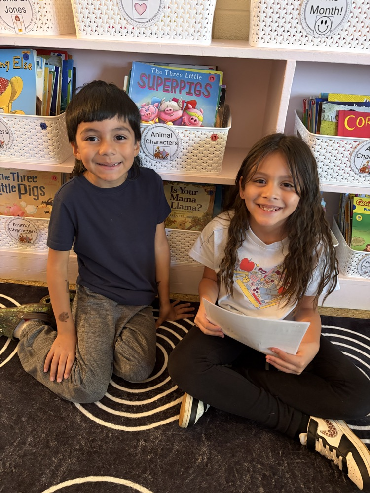 two students on the carpet reading essays