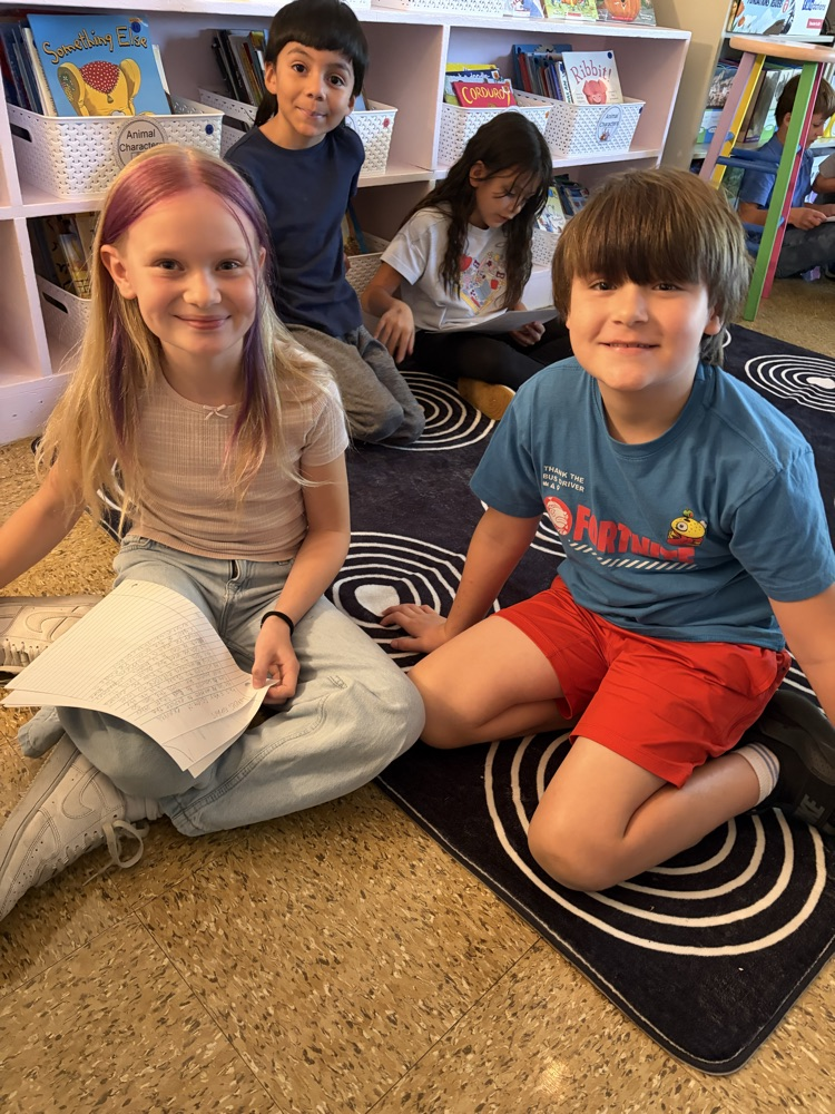 two students on the carpet reading essays