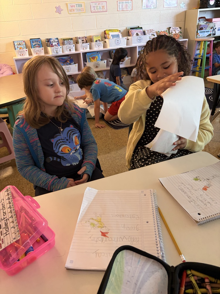 two students at desks reading essays