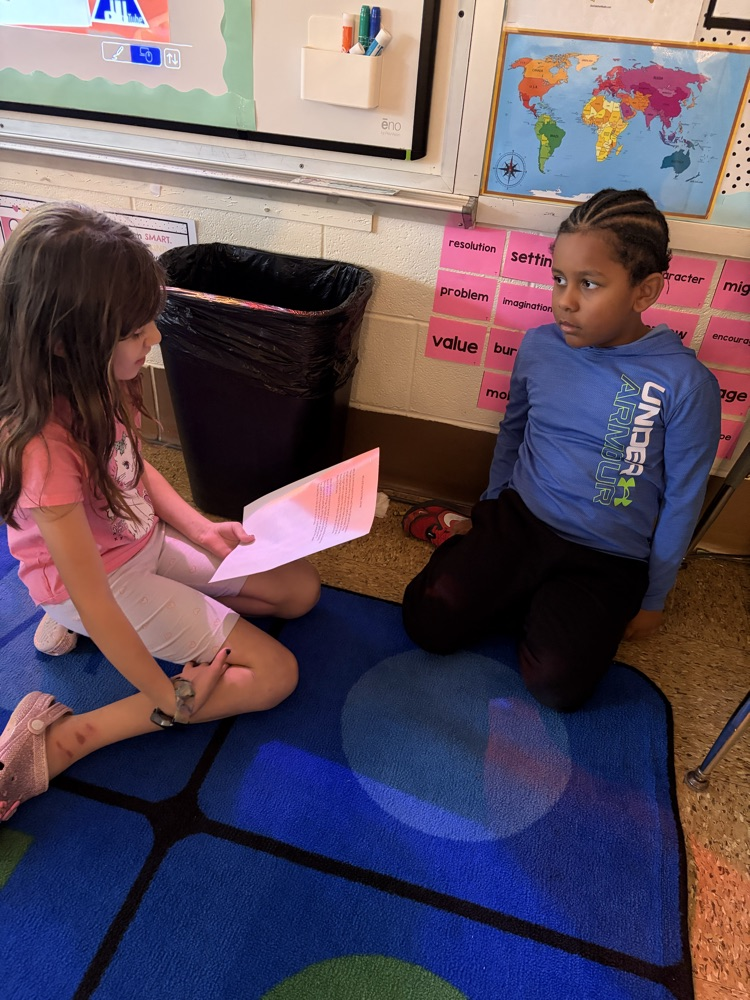 two students on the carpet reading essays