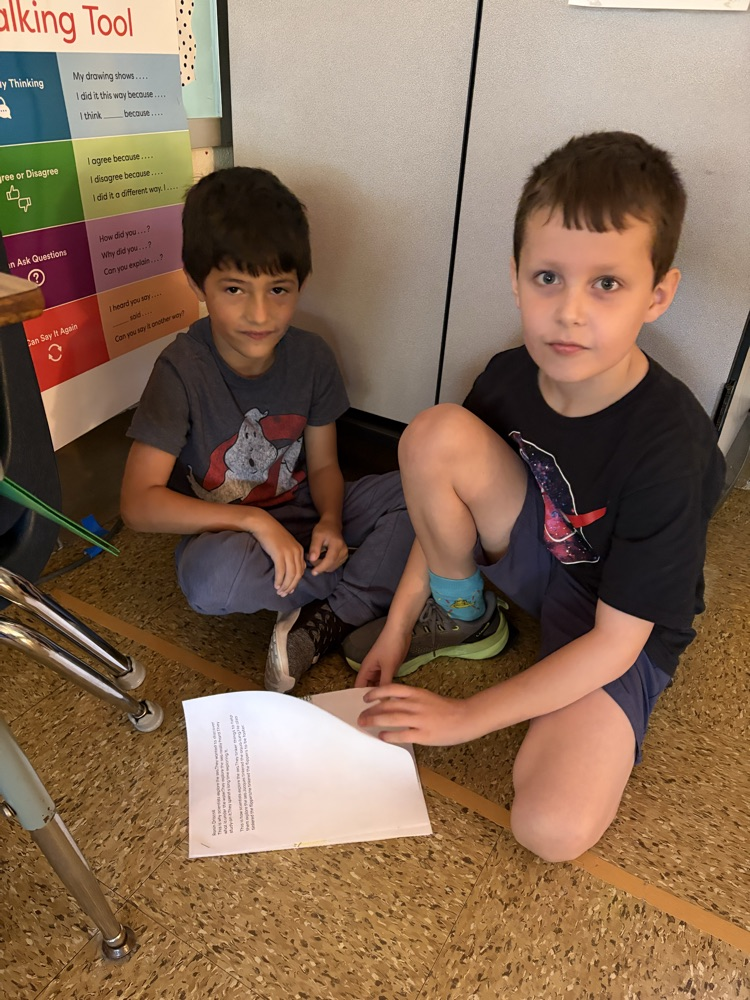 two students on the carpet reading essays