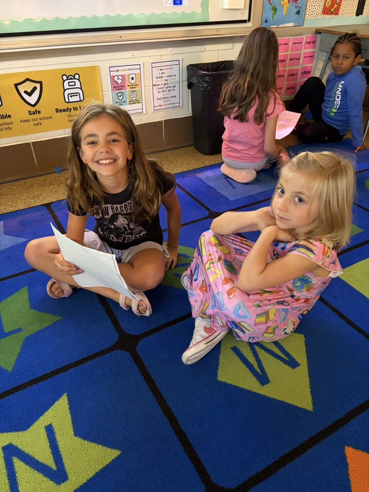 two students on the carpet reading essays