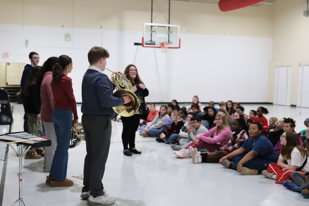 Instrument demonstration french horn showing students listening.