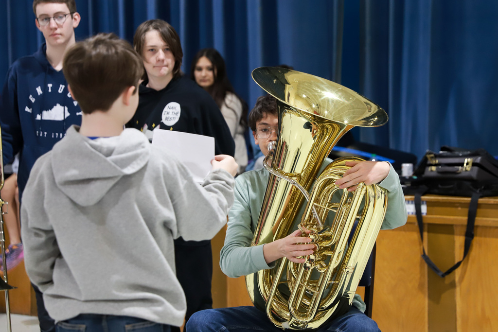 Instrument demonstration. Student holding music with another playing horn.