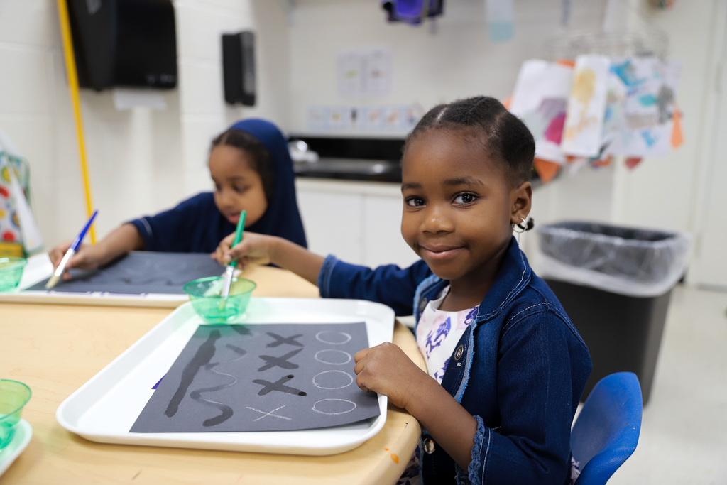 Student smiling at camera while dipping brush in water