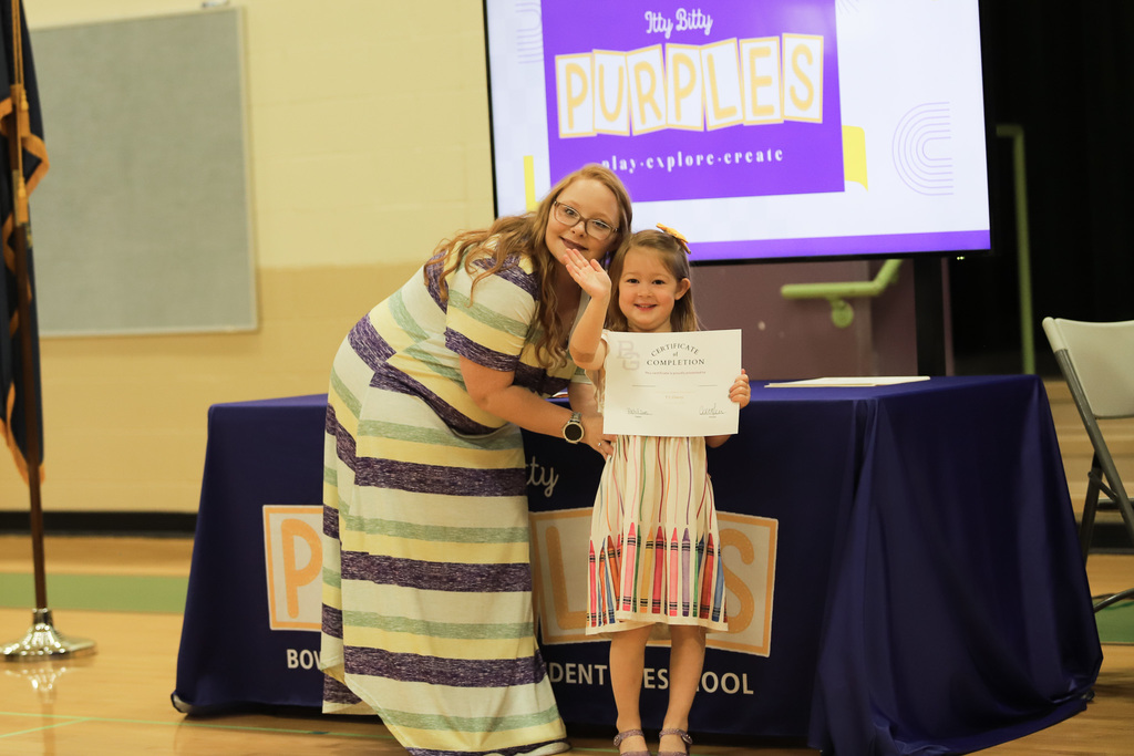 Student waving with certificate at PreK Promotion