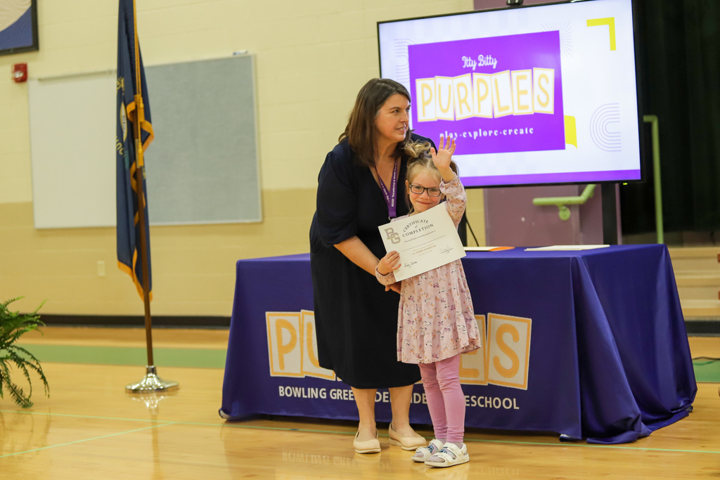 Student waving with certificate at PreK Promotion