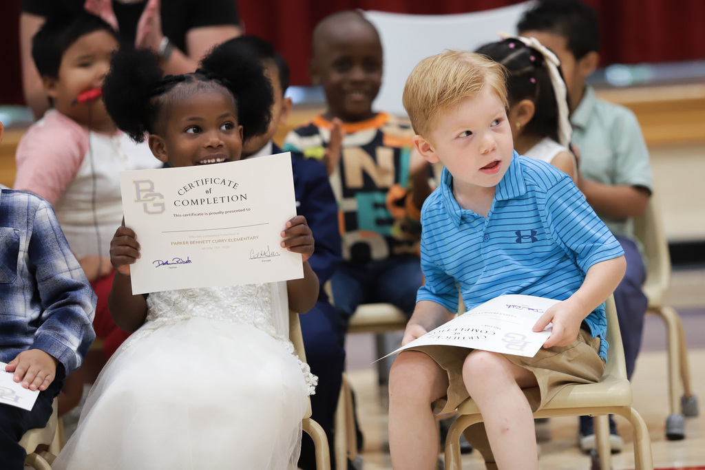 Students seated with certificates at PreK Promotion