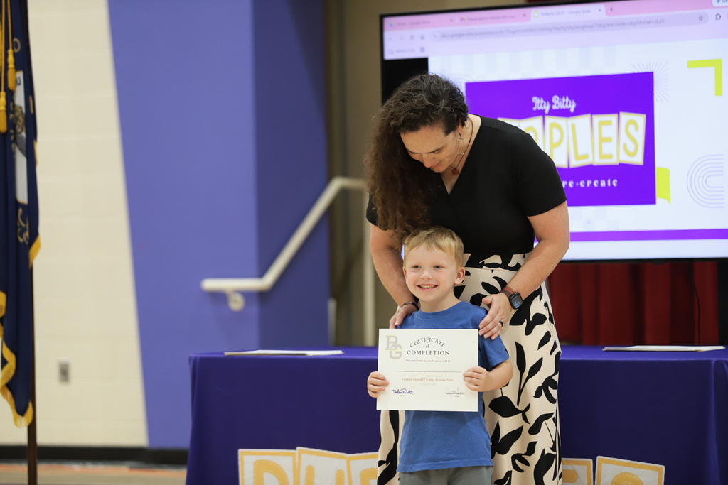 Student smiles with certificate at PreK Promotion