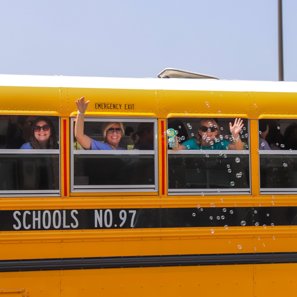 Teachers wave from school bus with bubbles