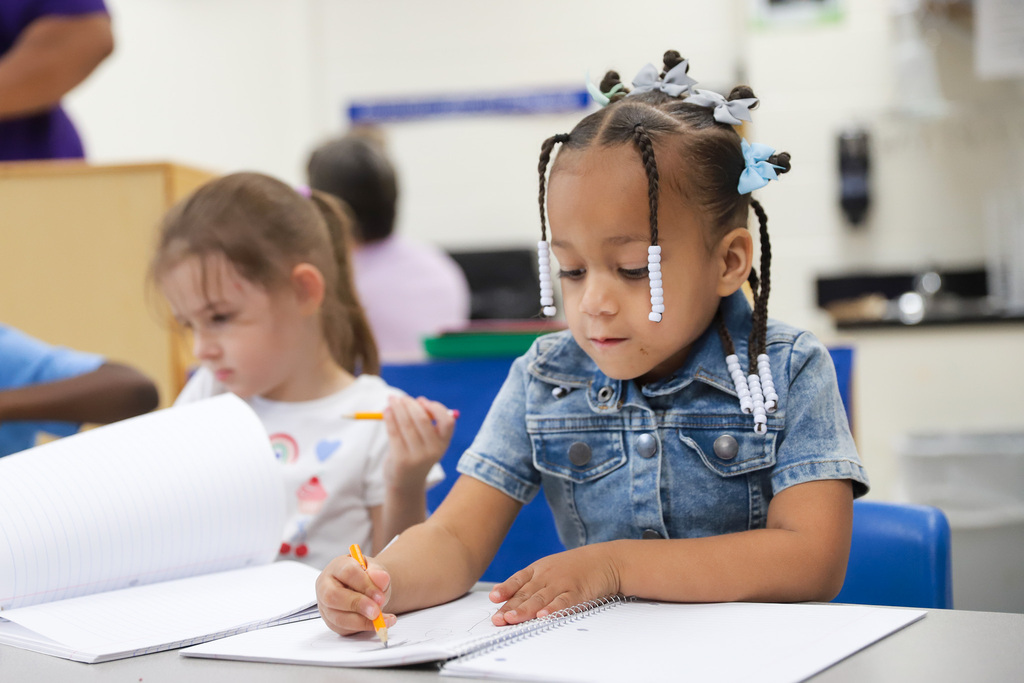 Preschool student writing in notebook