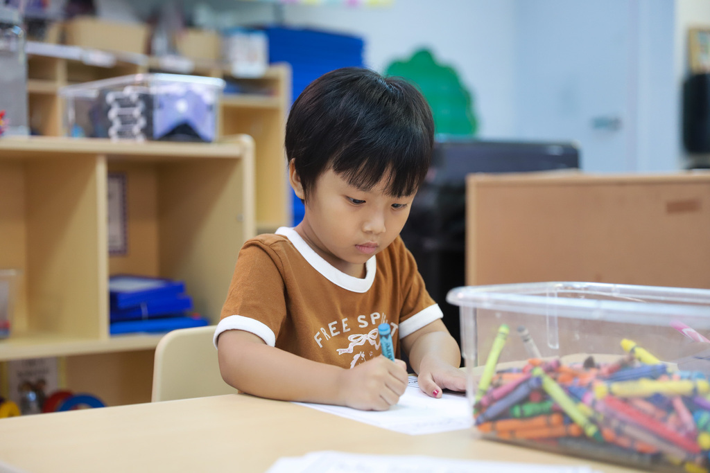Preschool student drawing with crayon