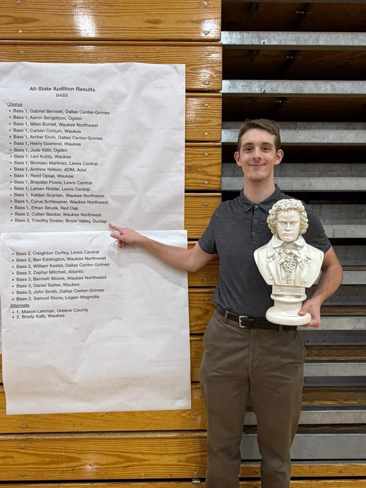 A student holding a Beethoven statue, pointing to his name on an Allstate choir acceptance list