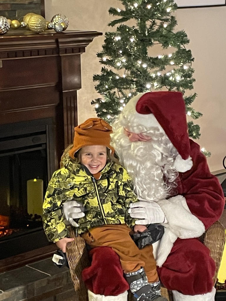 preschool child in winter gear sits on Santa's lap