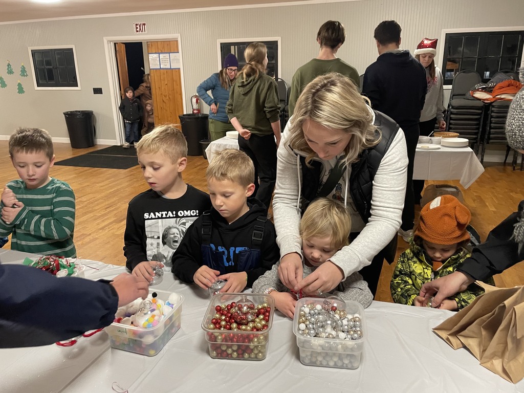 woman helps small children with Christmas craft