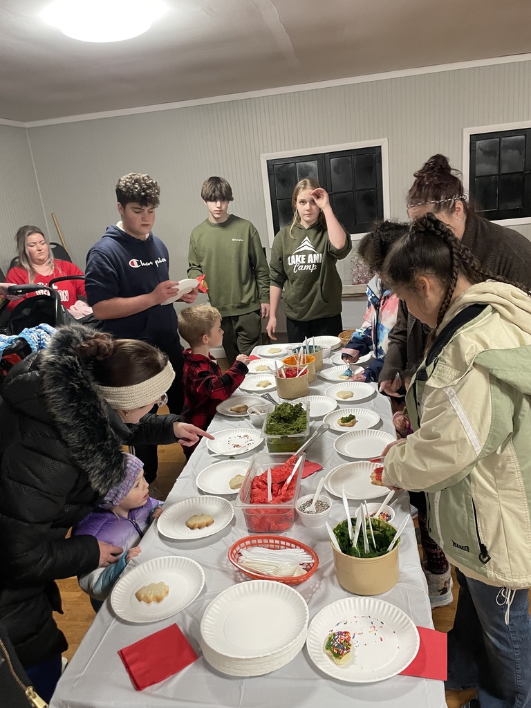 high school volunteers and parents help preschoolers decorate Christmas cookies