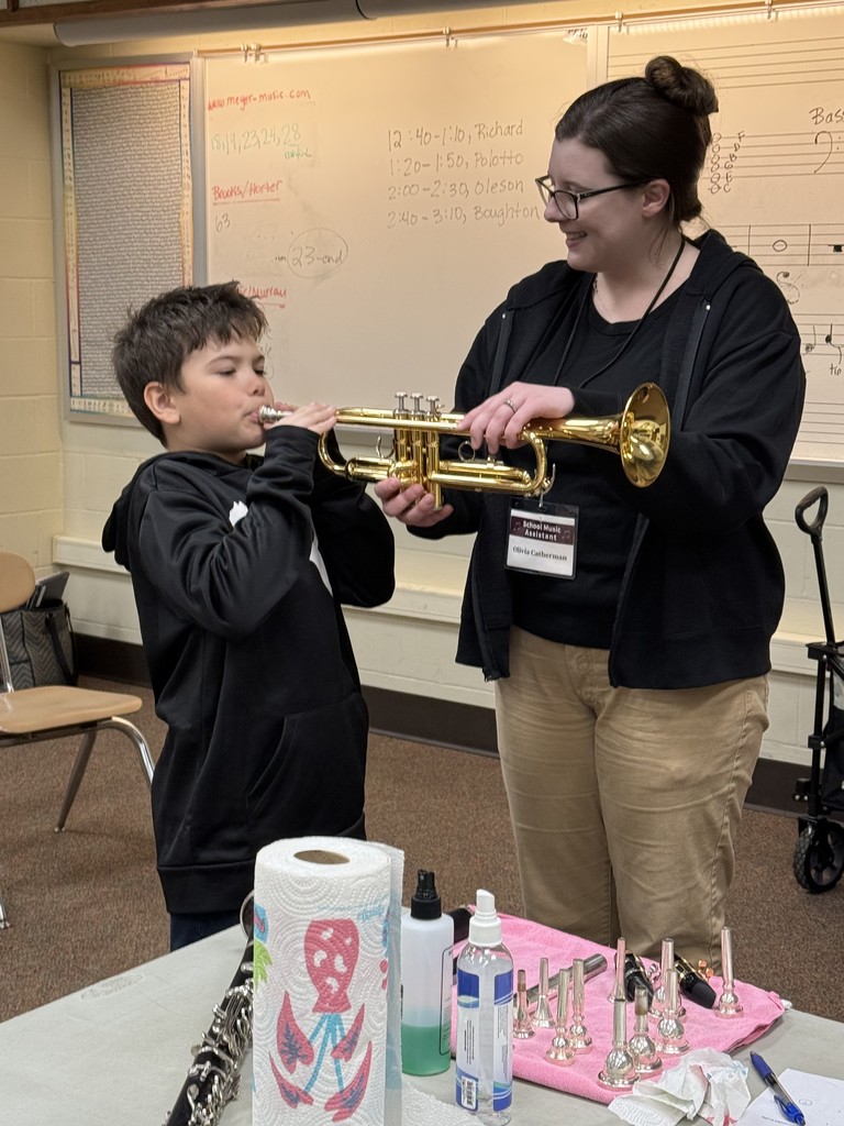 teacher showing young boy how to play trumpet