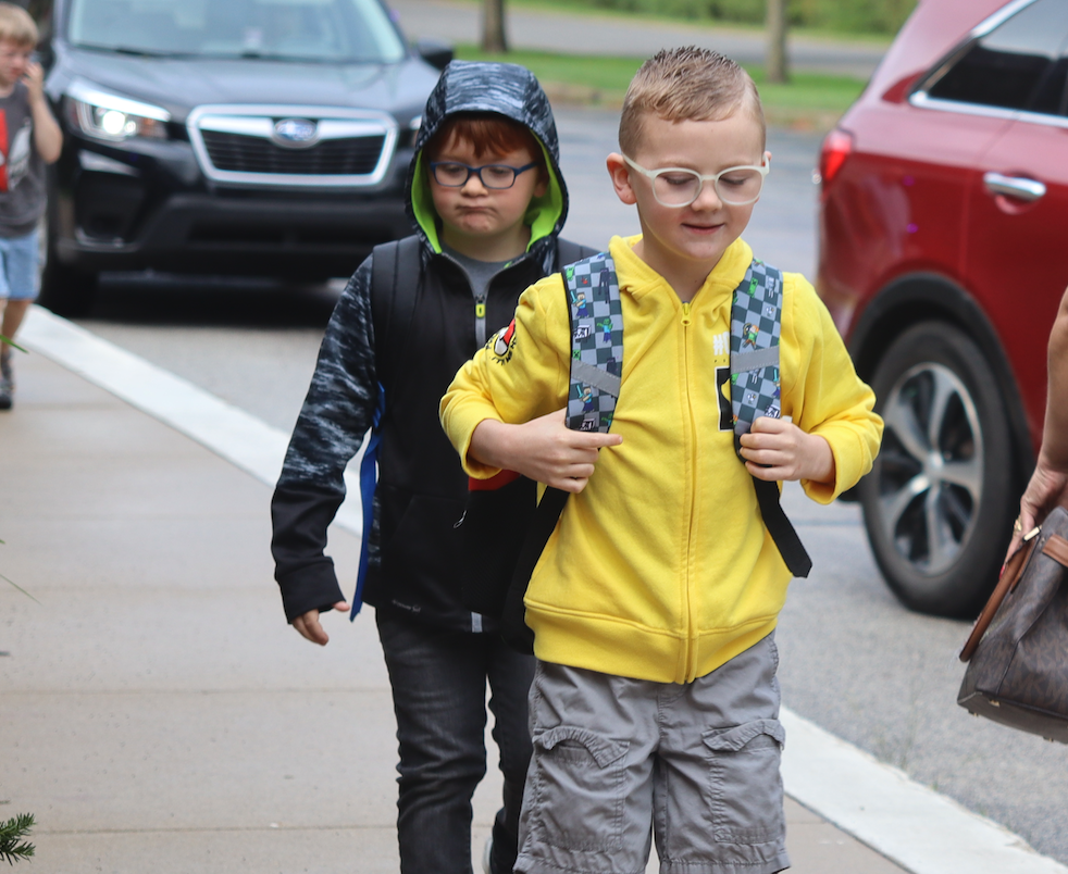 two little boys walking into the school with backpacks