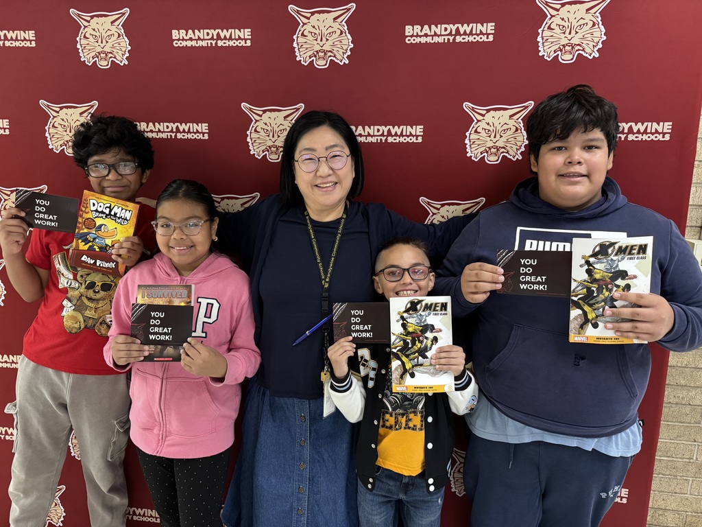 four kids standing with teacher with books and postcards