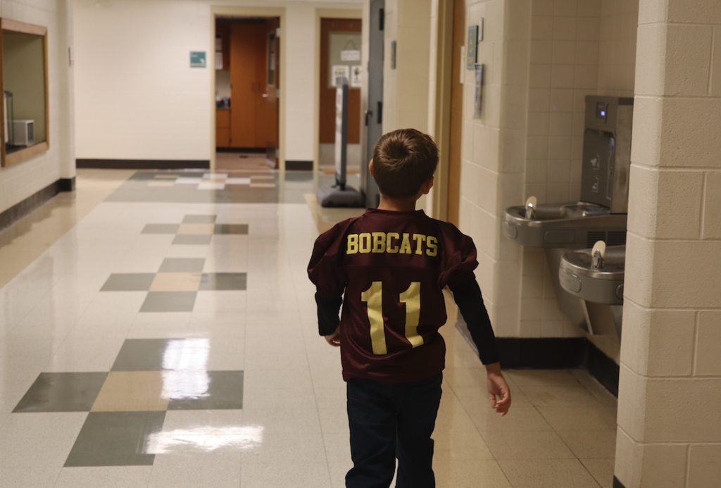small kid walking with football jersey