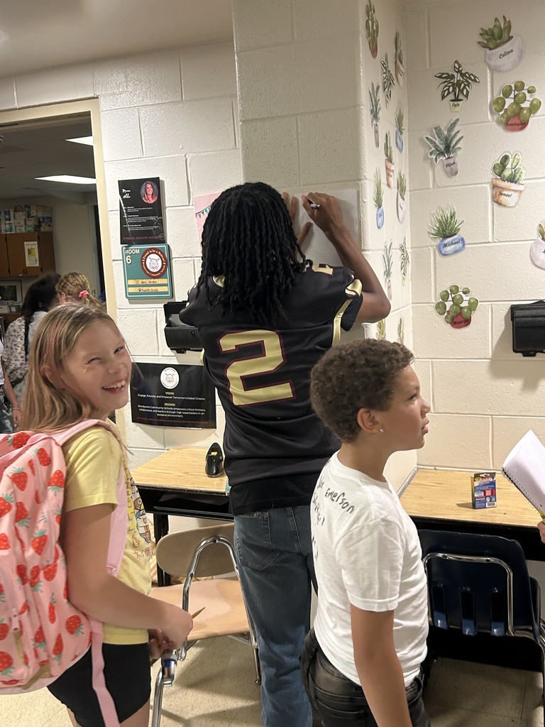 high school writing an autograph and kids standing waiting