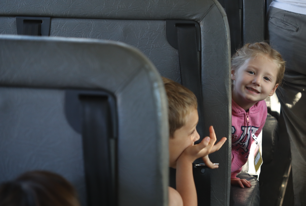 little girl smiling at the camera sitting on the bus