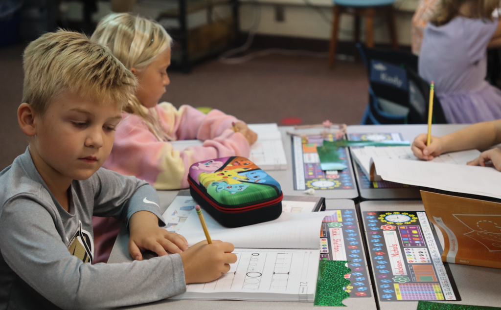 little boy in classroom practicing handwriting