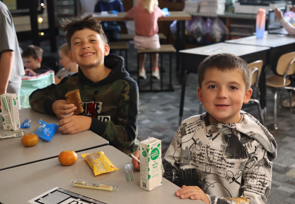 two young boys in class eating their breakfast