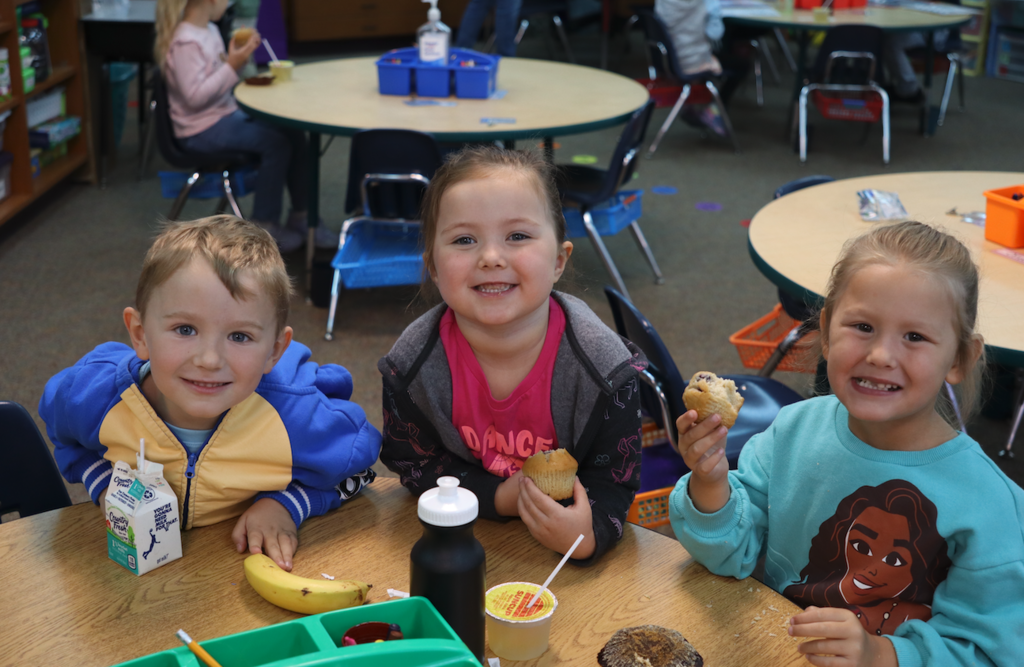 one boy and two girls smiling in the classroom