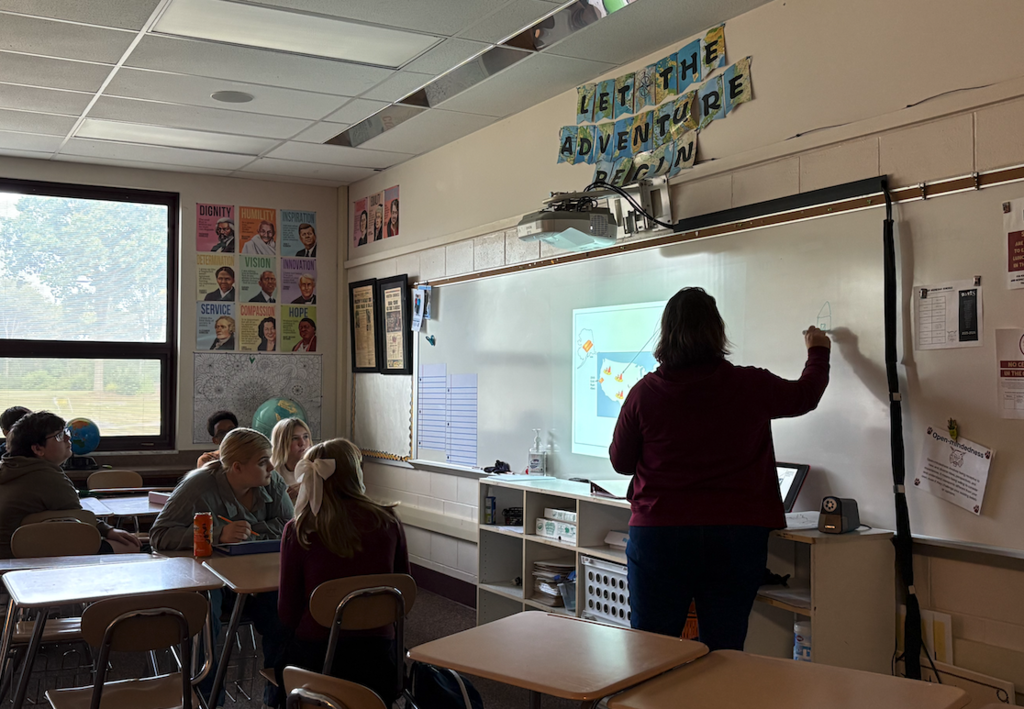 teacher at front of class writing on white board