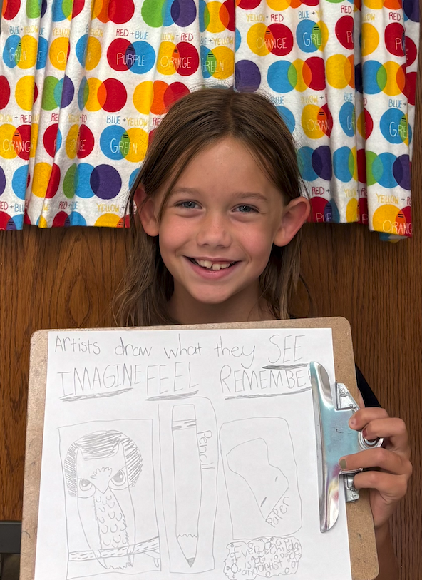 little girl holding up clipboard with drawing