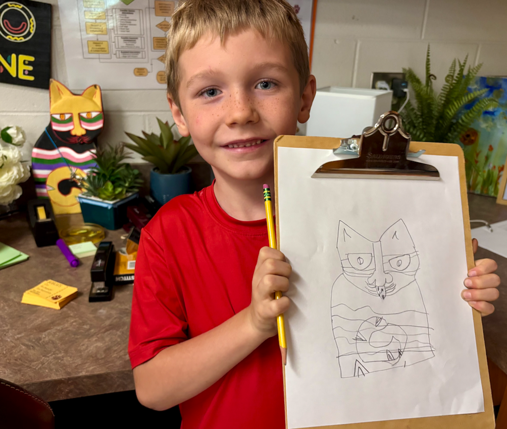 little boy drawing and holding up clipboard