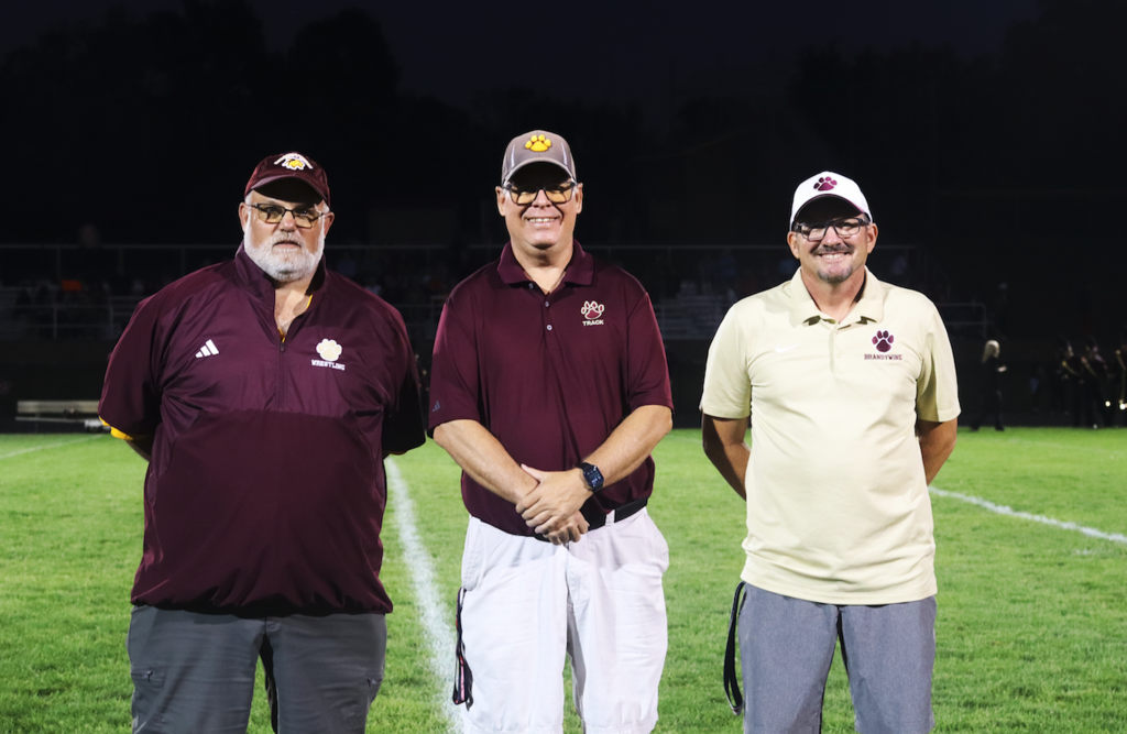 three coaches standing on field