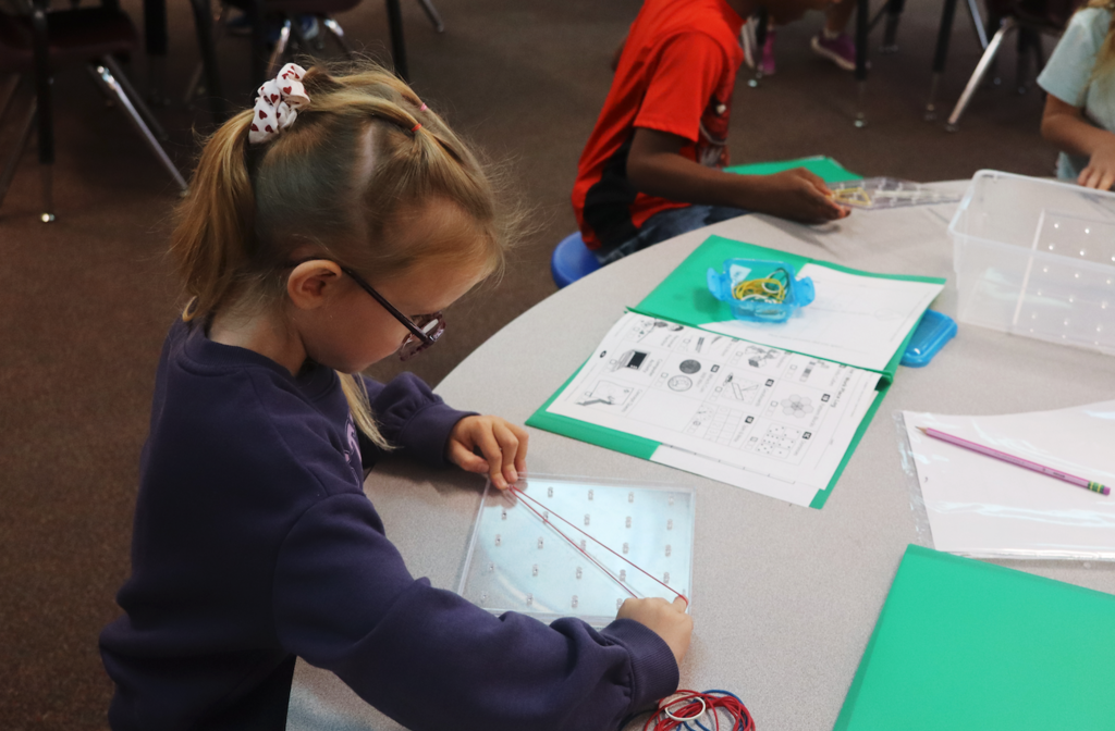 little girl creating a rubber band pattern