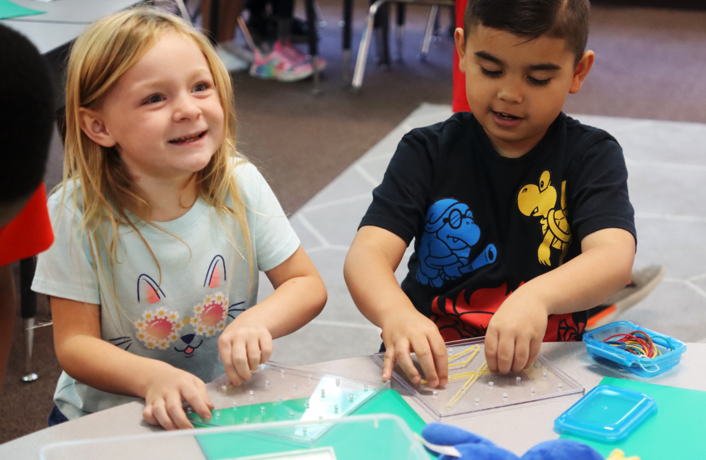two little kids playing with building a rubber band pattern