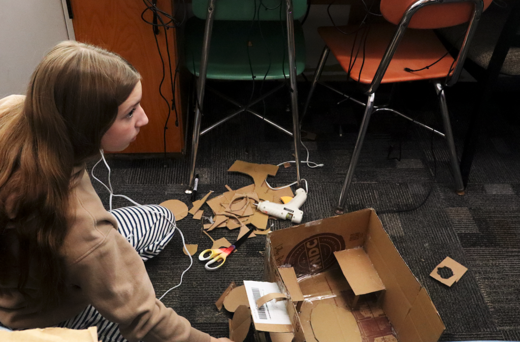 student glueing cardboard box