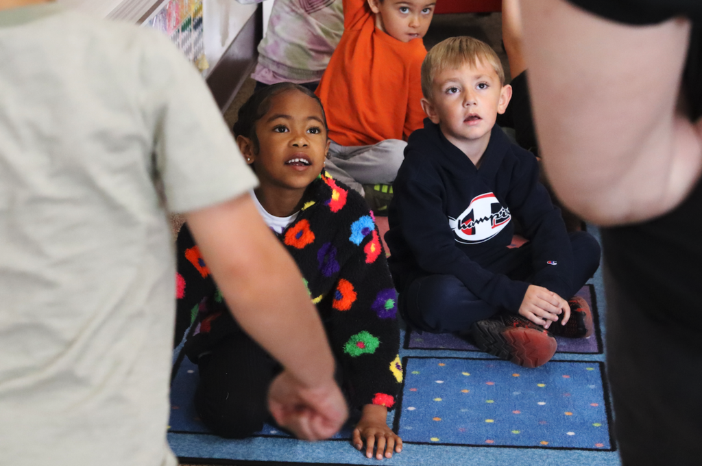 students sitting on rug in classroom