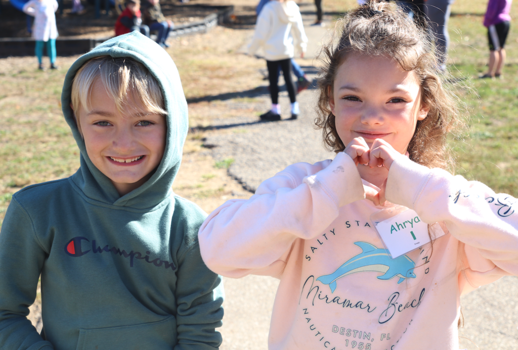 little boy and little girl holding up the heart sign on playground