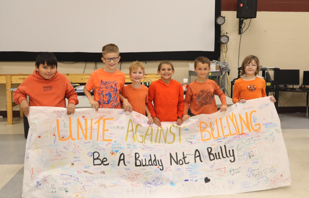 kids holding up a be a buddy not a bully sign