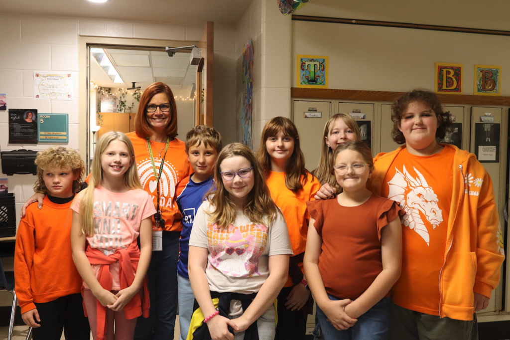 teacher and 8 kids in orange shirts