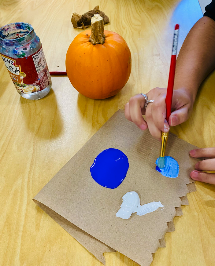 student putting paint on paintbrush