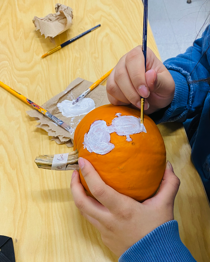 student painting pumpkin