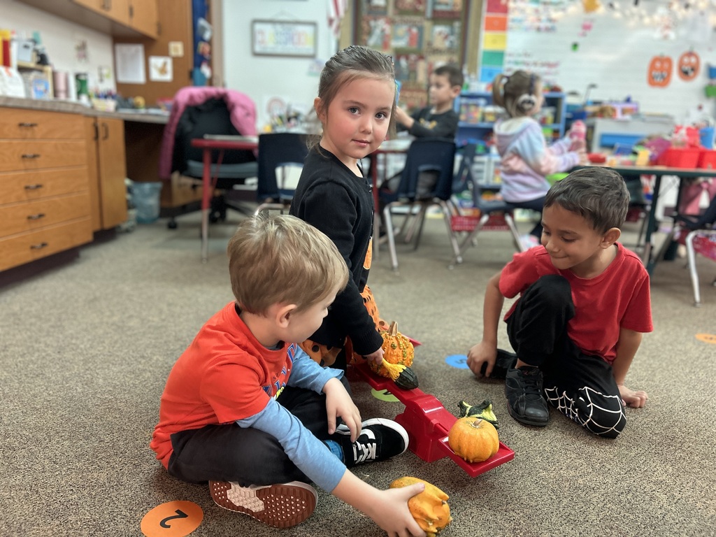little girl and two boys weighing gourds