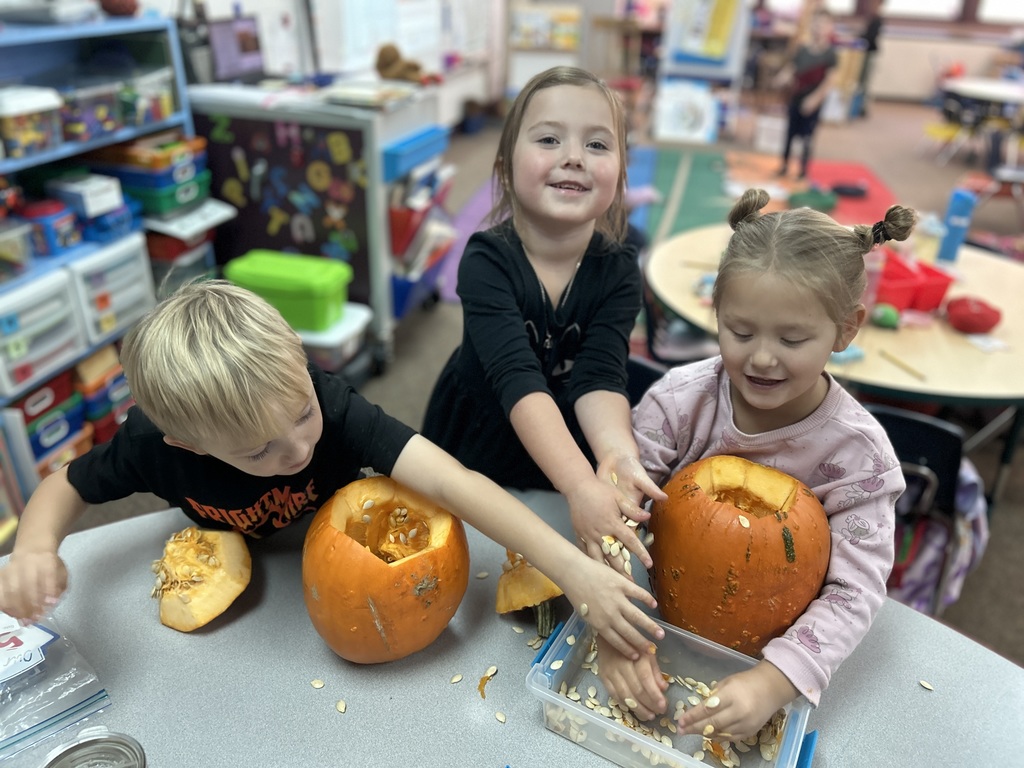two little girls and boy cleaning out pumpkin
