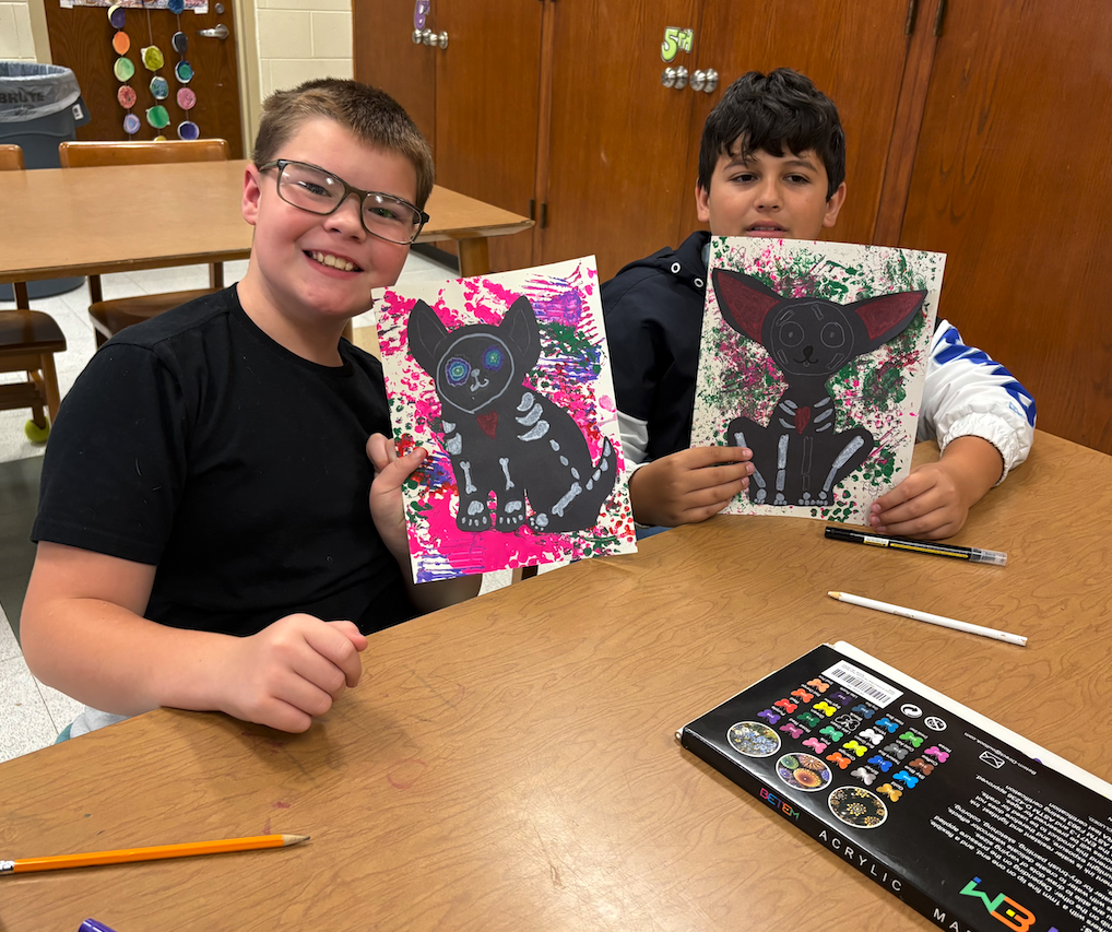 two boys holding up drawings of animals