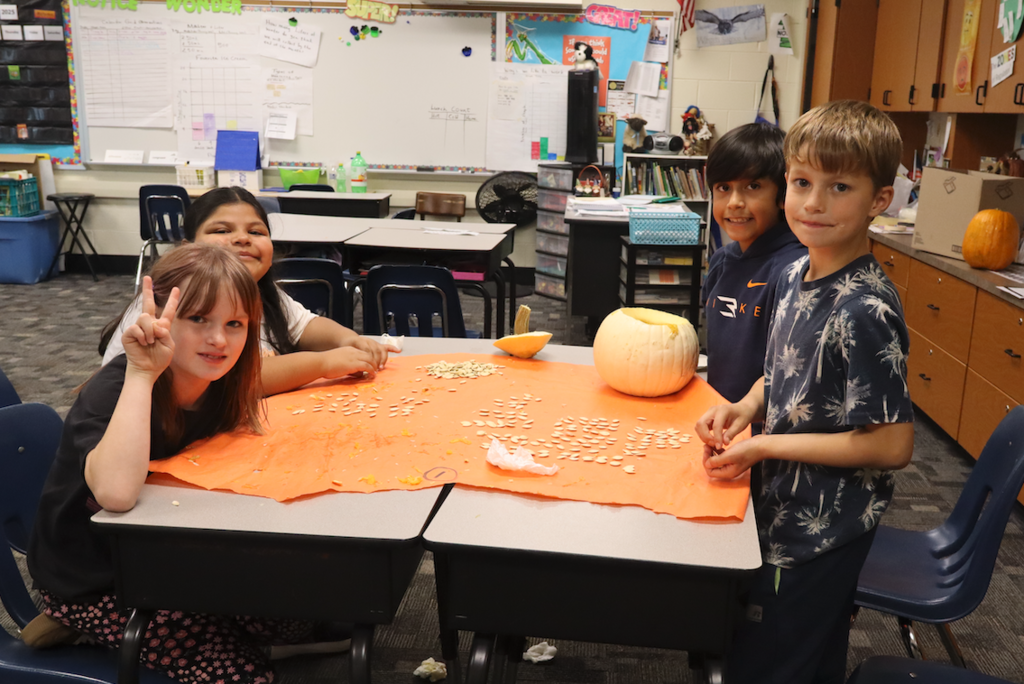 kids sitting at table with pumpkin and seeds