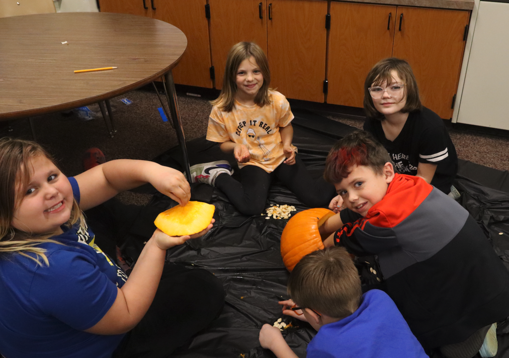 kids cutting inside to a pumpkin