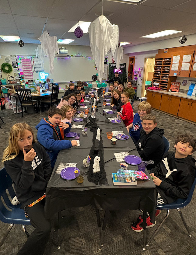 group of students sitting at long table eating snacks